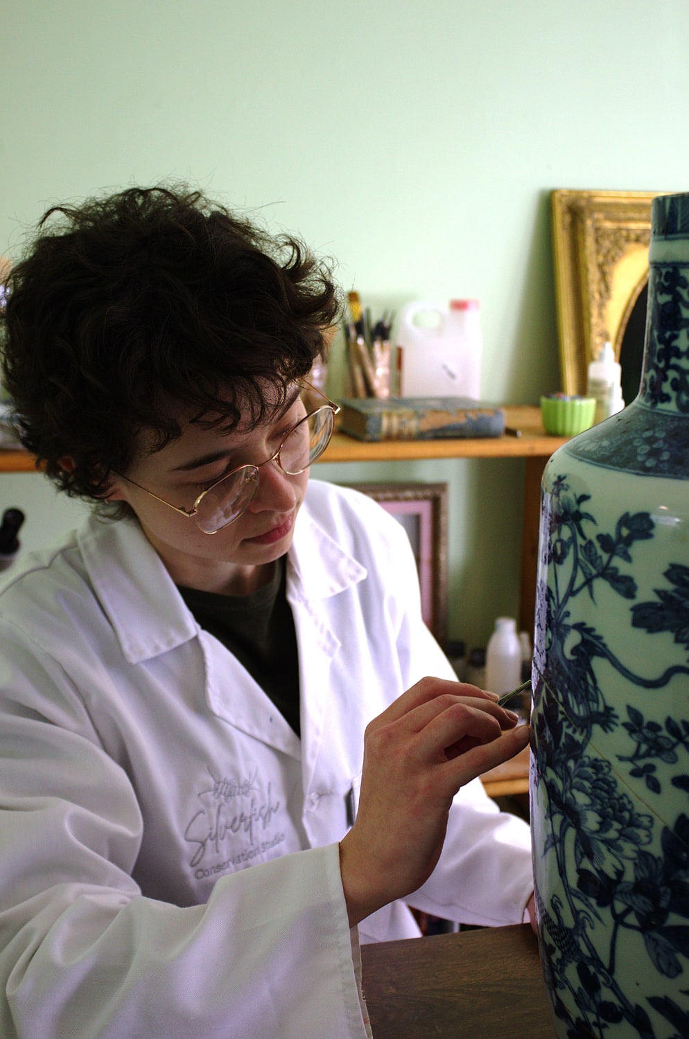 Chloe Cox retouching a blue-and-white vase in the studio